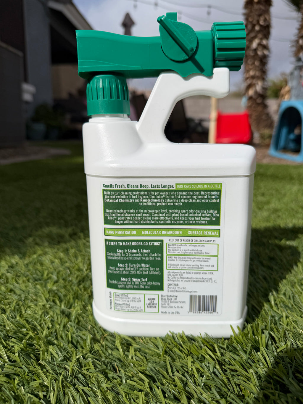 Dino Juice Spray bottle showing backside label with green nozzle on artificial turf