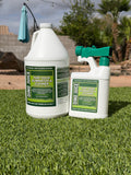 Two bottles of 'Dino Juice' turf odor eliminator and cleaner on grass with a blurred background