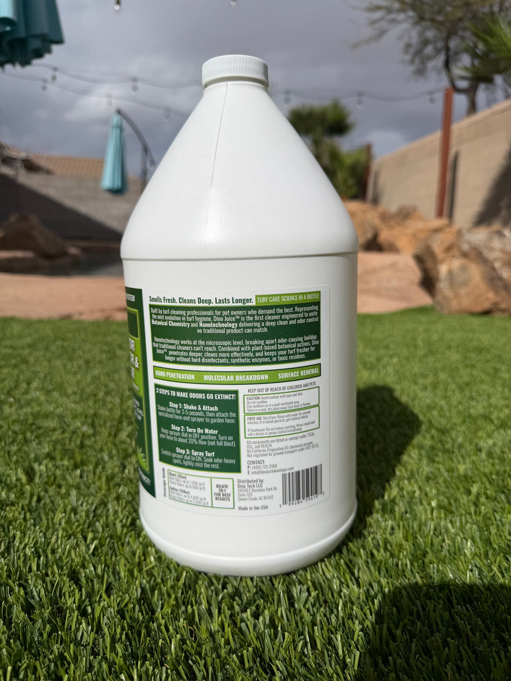 White bottle with green label saying turf odor eliminator and cleaner on a turf grassy surface